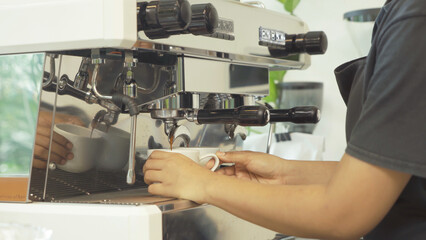 Close up of woman worker, barista in apron making a coffee by using coffee machine in kitchen bar of coffee shop. Business service. People lifestyle.