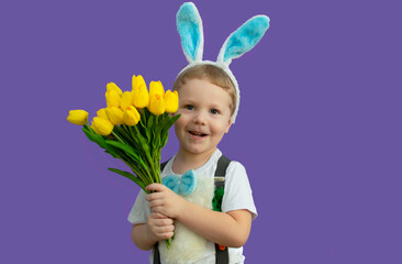 Happy Easter! A child in a rabbit costume holds a bouquet of yellow tulips. It's egg hunting time. A charming baby with funny bunny ears. Spring Easter holiday. The concept of a happy childhood