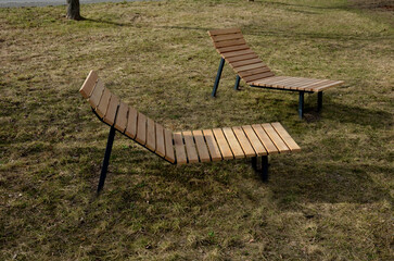 rocking chair on the pavement under the trees in the square. wooden deck chairs made of tropical...
