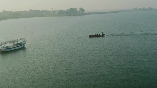 Aerial shot of Sightseeing Boat and patrol speed boat At Keenjhar Lake In Thatta, Pakistan at sunset.