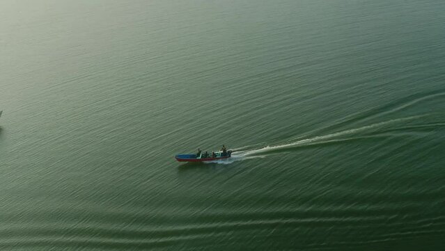 Follow aerial shot of Speed Boat At Keenjhar Lake In Thatta, Pakistan at sunset.