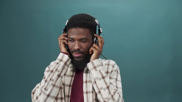 An african young man in a white shirt is listening to music and dancing