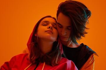 Teen couple hugging under orange neon light