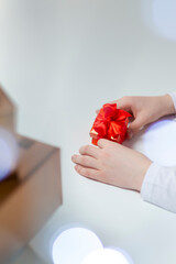 Closeup of Hands of Caucasian Female Holding Red Gift Box Along with Batch of Wrapped Present Boxes on Side.