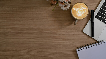 Flat lay cup of coffee, laptop computer and notepad on wooden background with copy space.