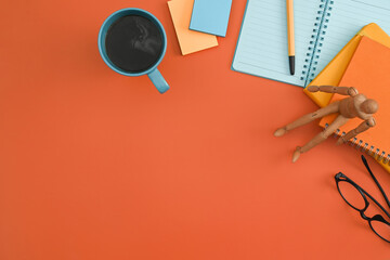Notebook, sticky notes, eyeglasses, coffee cup on orange background. Flat lay.