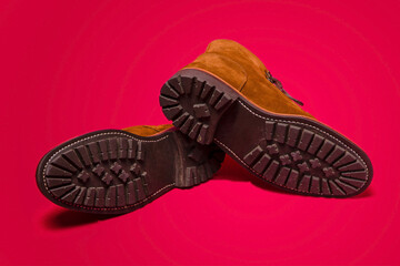 Footwear Concept. Pair of Tan Brown Suede Split Toe High Boots Closeup With Rude Rubber Sole Placed Together Turned On Red Background.