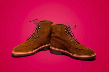 Footwear Concept. Pair of Tan Brown Suede Split Toe High Boots Closeup With Rude Rubber Sole Placed Together On Red Background.
