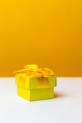 Closeup Image Of Wrapped Christmas and New Year Gift in Yellow paper Tiny Box Placed Over Yellow Trendy Background.
