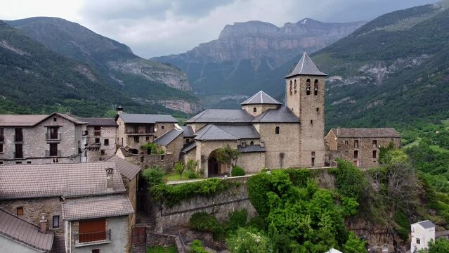 Torla in Ordesa Valley, Huesca, Aragon, Pyrenees, North Spain - Aerial Drone View (Fly Over) of the Church, Green Valley, Blue River and Dark Mysterious Mountains