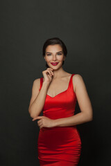 Happy smiling woman with makeup in amazing red dress celebrating new year party on black background.