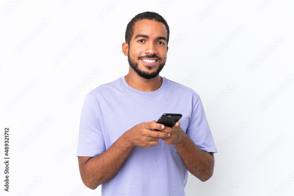 Wall mural young ecuadorian man isolated on white background sending a message with the mobile