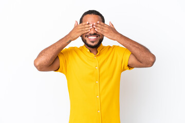 Young Ecuadorian man isolated on white background covering eyes by hands and smiling