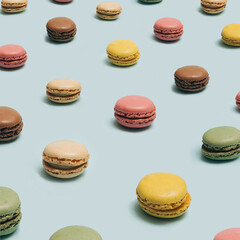 Many macarons, with different colors and tastes arranged in a modern pattern perspective. Patisserie yummy artisan concept. Pastel blue background.