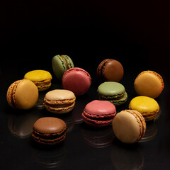 Patisserie yummy artisan concept. Many macarons, with different colors and taste, sit at a glassy plate. Awesome black background.
