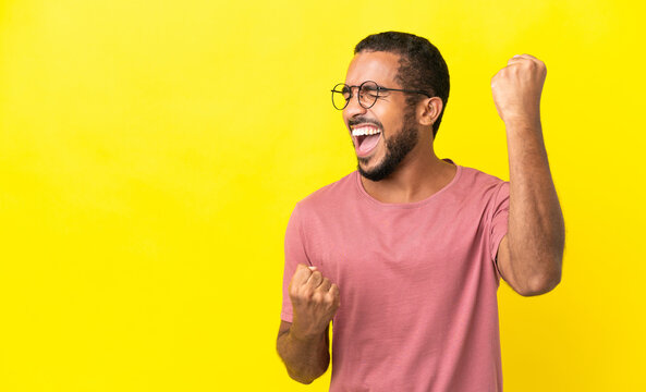 Young latin man isolated on yellow background celebrating a victory