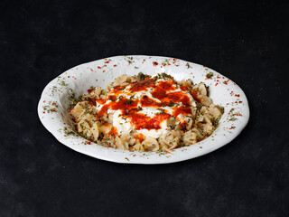 Plates of traditional Turkish food. Manti (Turkish ravioli) with yogurt sauce. Black background