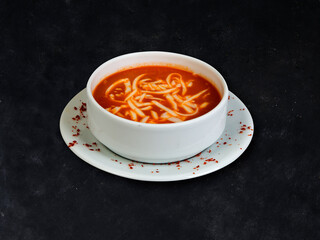Tomato soup with cheese in a bowl. Dark background.