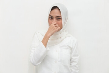 Asian muslim woman holding her nose because of a bad smell
