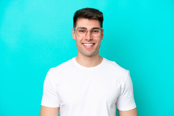 Young caucasian man isolated on blue background With glasses with happy expression