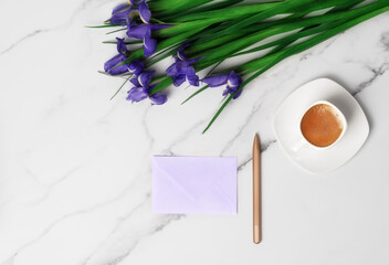 Cup of hot morning coffee and violet irises on marble background. Flat lay with copy space for text. Greeting card for Women's Day and March 8th.
