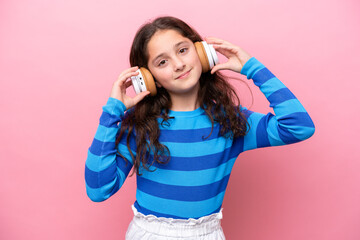 Little girl isolated on pink background listening music