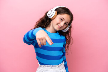 Little girl isolated on pink background listening music