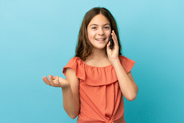 Fototapeta premium Little caucasian girl isolated on blue background keeping a conversation with the mobile phone with someone