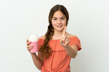 Little caucasian girl with strawberry milkshake isolated on white background showing and lifting a finger