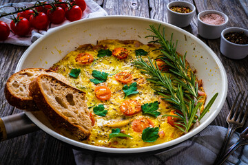 Breakfast - omelette with bacon, bread and vegetables in frying pan
