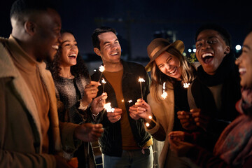 Diverse group of friends laughing at a party on a rooftop terrace. Nightlife in the city, Lighting...