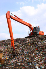 Backhoe working on garbage dump in landfill.