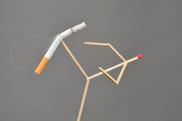 Quit Smoking Concept - match man kicks off a cigarette over gray background
