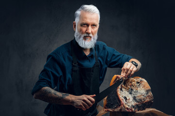 Professional old butcher preparing huge beefsteak at table