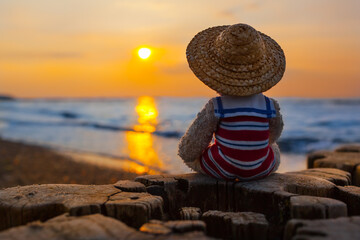 Tranquil Evening Time at Beach Shore / Teddy bear wear nostalgic sailor suit and straw hat, enjoy end of day at sea with beautiful sunset (copy space) - 489336773