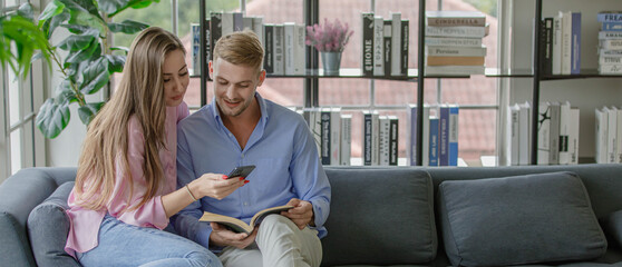 Millennial young Caucasian lover married couple sitting cuddling together on cozy sofa beautiful...