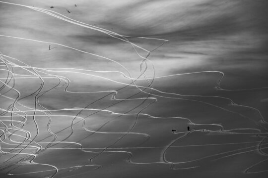 Black and white photo of a ski resort. Ski tracks and snowboard
