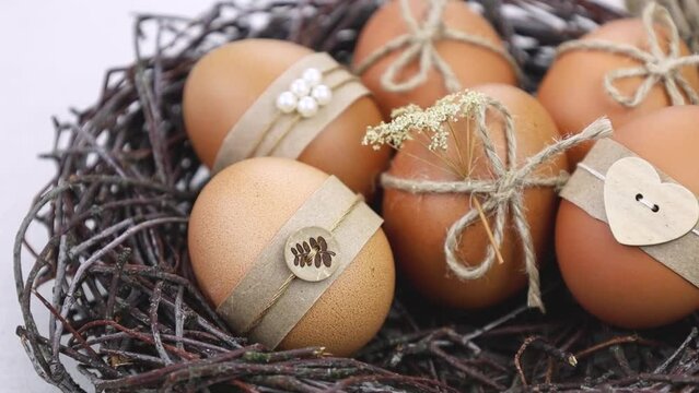 Easter eggs in nest on wite background. Easter eggs decorated with natural materials. Flat lay. Minimalistic decor for Easter. DIY
