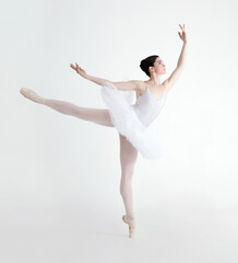 Perfect arabesque. Elegant young ballerina dancing en pointe against a white background.