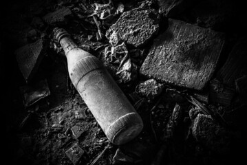 Thrown away bottle on dirty floor in black and white.