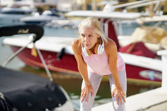 Senior woman in fitness clothing taking a break during exercise.