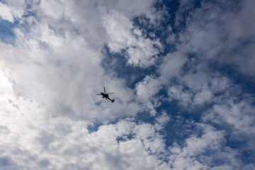 Silhouette of an Italian military helicopter in motion against a Blue Sky with Clouds, Italian Alps, Trentino-Alto Adige, Italy, Europe.
