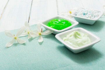 cosmetic creams and white flower, on textile, white painted wooden