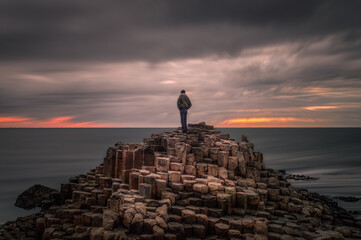 Lonely traveler on the top of the Giant's Causeway at sunset, Northern Ireland