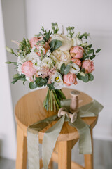 Bouquet of flowers stands on a wooden chair in the bedroom. Peonies and roses