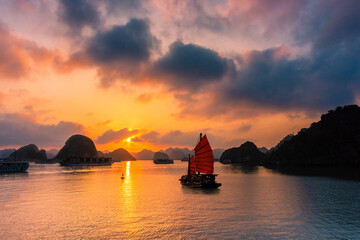 Traditional boat sailing during an amazing sunset over Ha Long Bay, Vietnam