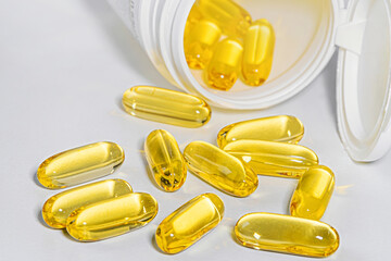 The concept of healthy nutrition, diet and omega-3 supplements - close-up of capsules poured out of a jar.