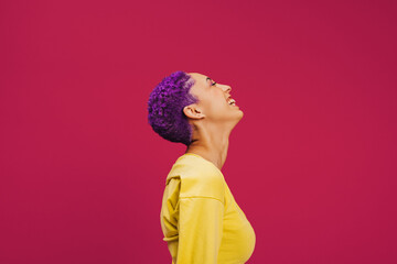 Purple haired young woman laughing cheerfully in a studio