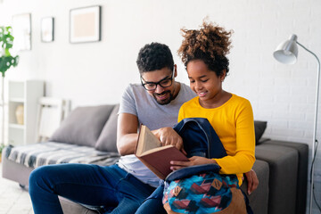 Black father helping daughter pack her bag for school