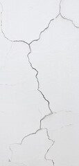 The vertical image of the white painted plaster wall is so cracked that long fissures are visible and rainwater can seep through. This may be due to improper mixing of mortar or soil subsidence. patte